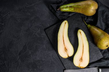 Armut ve armut yarıları. Çiftlik eko meyveleri. Siyah arka plan. Üst Manzara. Metin için boşluk