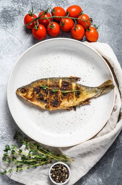 Beyaz tabakta kızarmış sazan balığı. Nehir organik balığı. Gri arka plan. Üst görünüm