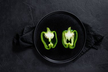 Yeşil tatlı biber, iki yarım. Siyah arka plan. Üst Manzara. Metin için boşluk.