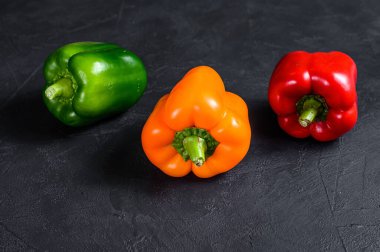 Yeşil, turuncu ve kırmızı dolma biber. Siyah arka plan. Üst Manzara. Metin için boşluk.