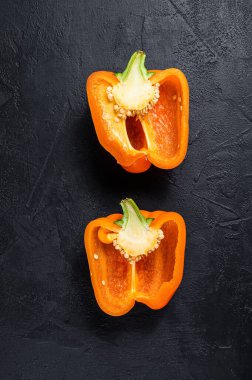 Portakallı tatlı biber, iki yarım. Siyah arka plan. Üst Manzara. Metin için boşluk.