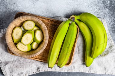 Tahta tepside yeşil muzlar. Gri arka plan. Üst Manzara. Tropik meyve