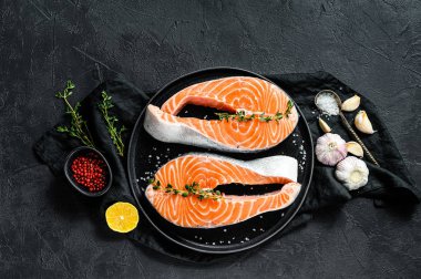 Baharatlı tabakta çiğ somon bifteği. Atlantik balığı. Siyah arka plan. Üst görünüm