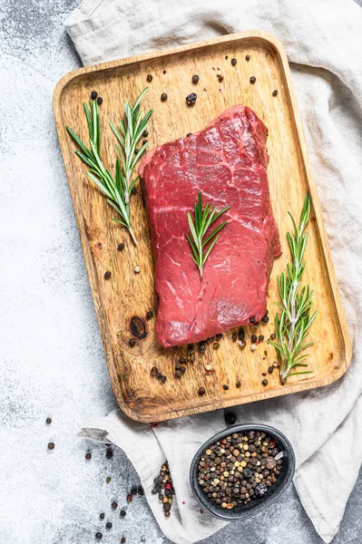 Raw new York strip steak on a wooden tray. Beef meat. Gray background. Top view