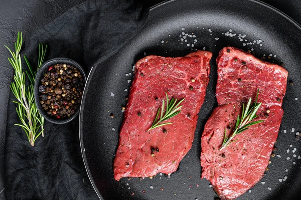 Bife cru de lombo em uma frigideira. Carne de vaca. Fundo preto. Vista superior — Fotografia de Stock