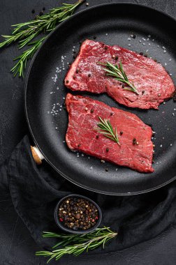 Kızartma tavasında çiğ fileto biftek. Et eti. Siyah arka plan. Üst görünüm