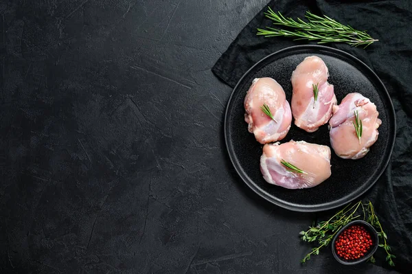 Raw chicken thigh fillet without skin. Farm poultry meat. Black background. Top view. Space for text