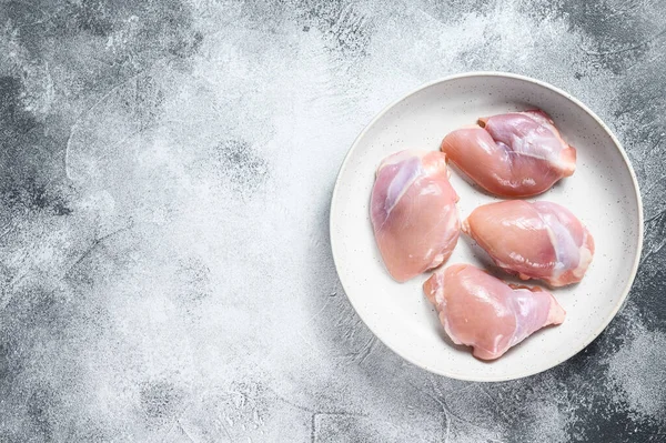 Raw chicken thigh fillet. Gray background. Top view. Space for text