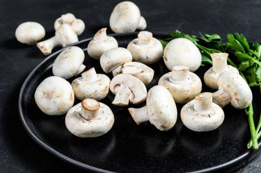 Tabakta taze mantar şampiyonu. Siyah arka plan. Üst görünüm