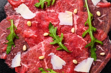 Arugula ve parmesan peynirli mermer sığır carpaccio. Siyah arka plan. Üst görünüm