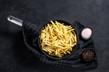 Kızartma tavasında donmuş patates kızartması. Siyah arka plan. Üst Manzara. Metin için boşluk