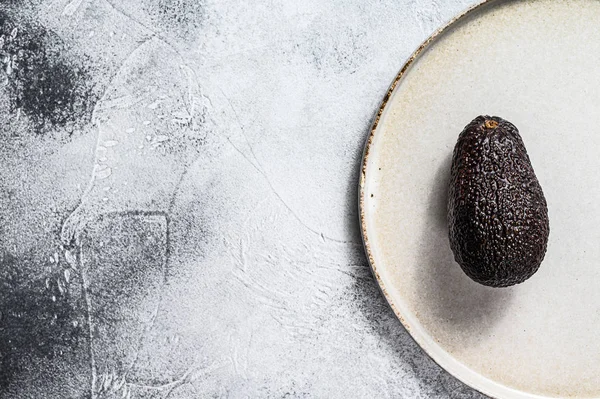 Aguacate en un plato de barro. Fondo gris. Vista superior. Espacio para texto — Foto de Stock