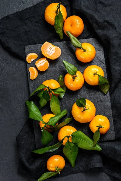 Mandarinen, Mandarinen mit Blättern schwarzer Hintergrund. Ansicht von oben — Stockfoto