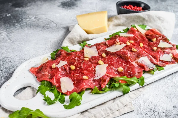 Black angus beef carpaccio with parmesan cheese. Gray background. Top view — Stock Photo, Image