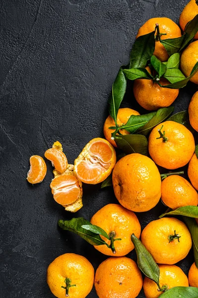 Tangerines, mandarines with leaves. Black background. Top view. Space for text