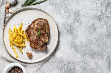 Kızarmış domuz bifteği ve patates kızartması. Gri arka plan. Üst Manzara. Metin için boşluk
