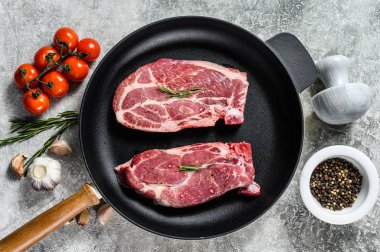 Kızartma tavasında çiğ biftek. Mermer çiftlik eti. Gri arka plan. Üst görünüm