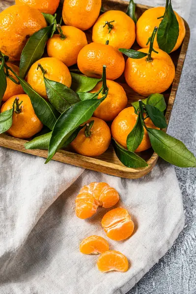 stock image Fresh mandarin oranges fruit or tangerines with leaves in a wooden bowl. Gray background. Top view