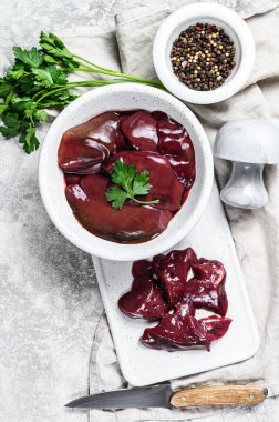 Bir kasede çiğ tavuk ciğeri. Gri arka plan. Üst görünüm