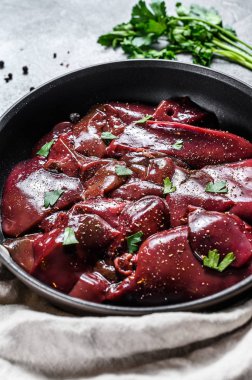 Kızartma tavasında çiğ hindi ciğeri. Gri arka plan. Üst görünüm