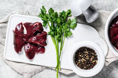 Bir kasede çiğ tavuk ciğeri. Gri arka plan. Üst görünüm