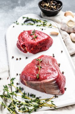 Mermer sığır filetosu. Beyaz kesim tahtasında çiğ fileminyon biftek. Gri arka plan. Üst görünüm