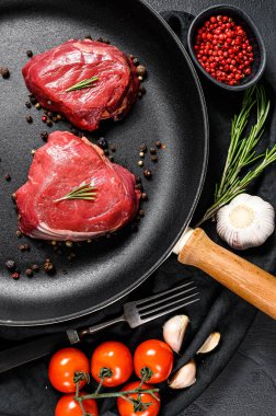 Kızartma tavasında çiğ fileminyon biftek. Sığır filetosu. Siyah arka plan. Üst görünüm