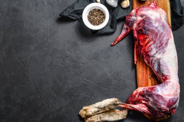 Tüm orman yabani tavşanı, ahşap güvertede çiğ et, eski siyah kır masası. Üst görünüm, boşluk kopyala