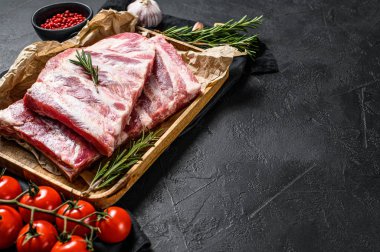 Biberiyeli taze domuz pirzolası ve ahşap bir kasede sarımsak. Siyah arka plan. Üst Manzara. Metin için boşluk