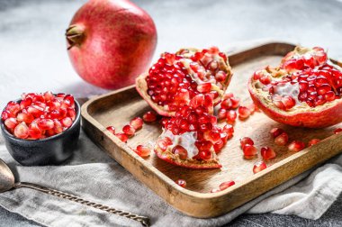 Olgun nar ve tahtadan bir kasede tohum. Organik meyve. Gri arka plan. Üst görünüm