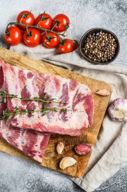 Biberiye, biber ve sarımsaklı taze çiğ domuz pirzolası. Çiftlik organik eti. Gri arka plan. Üst görünüm