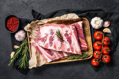 Biberiyeli taze domuz pirzolası ve ahşap bir kasede sarımsak. Siyah arka plan. Üst görünüm