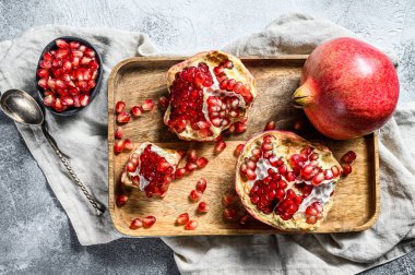 Tahta bir kasede taze, olgun bir nar. Organik meyve. Gri arka plan. Üst görünüm