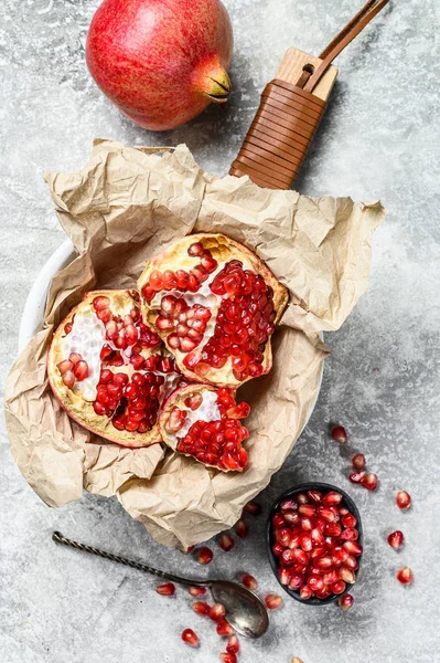 Rijp granaatappel en zaden op een houten snijplank. Biologisch fruit. Grijze achtergrond. Bovenaanzicht — Stockfoto