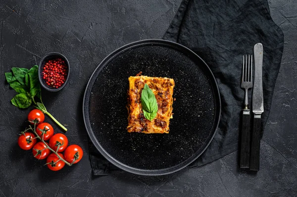 Кусок вкусной горячей лазаньи. Традиционная итальянская еда. Чёрный фон. Вид сверху — стоковое фото