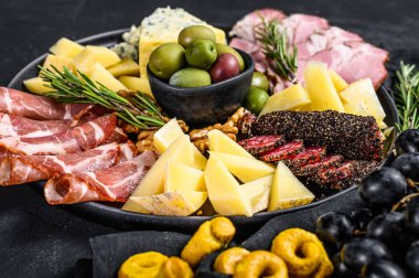 Jambon, prosciutto, salam, mavi peynir, mozarella ve zeytinli Antipasto tabağı. Siyah arka plan. Üst görünüm