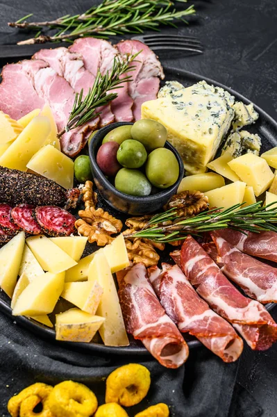 Antipasti-Platte mit Schinken, Schinken, Salami, Blauschimmelkäse, Mozzarella und Oliven. Schwarzer Hintergrund. Ansicht von oben — Stockfoto