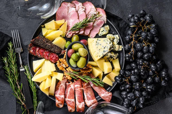 Antipasto con prosciutto, prosciutto, salame, formaggio blu, mozzarella e olive. Fondo nero. Vista dall'alto — Foto Stock