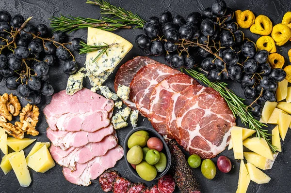 Antipasto tallrik med skinka, prosciutto, salami, blåmögelost, mozzarella och oliver. Svart bakgrund. Ovanifrån — Stockfoto