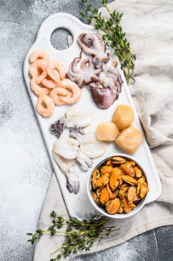 Seramik doğrama tahtasında çiğ deniz ürünleri karışımı. Gri arka plan. Buraya...