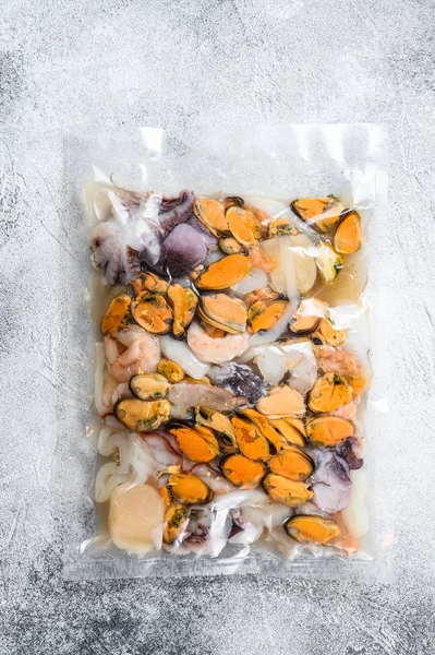 Raw seafood mix in vacuum packaging. Gray background. Top view
