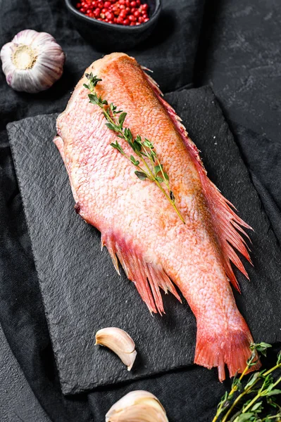 Raw red sea perch on a stone Board with thyme. Black background. — Stock Photo, Image