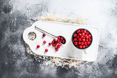 Demir bir kupada olgun kırmızı kızılcıklar. Gri arka plan. Üst Manzara. Metin için boşluk