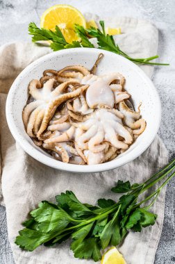 Beyaz kasede maydanozlu çiğ ahtapot ve limon. Organik deniz ürünleri. Gri arka plan. Üst görünüm