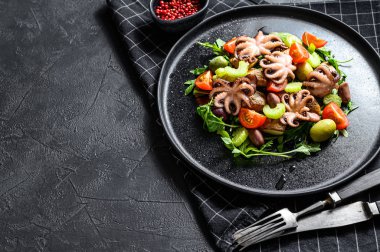 Izgara ahtapot, patates, roka, domates ve zeytinli salata. Siyah arka plan. Üst Manzara. Metin için boşluk