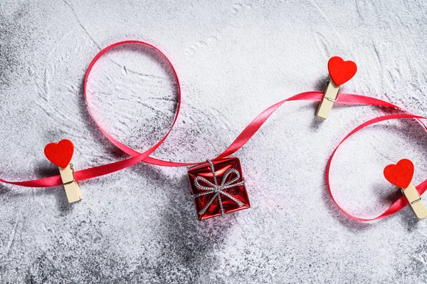 Het concept van Valentijnsdag. Geschenkdoos met rood lint en hartjes. Grijze achtergrond. Bovenaanzicht. Ruimte voor tekst — Stockfoto