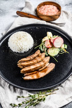 Hindi göğsü bifteği, kümes hayvanları, bir tabak pirinç ve salata. Gri arka plan. Üst görünüm