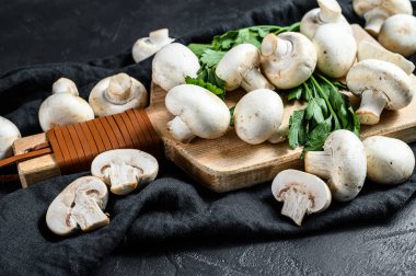 Tahta kesme tahtasında çiğ mantar şampiyonu. Siyah arka plan. Üst görünüm