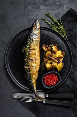 Kızarmış patates ve mantarlı füme uskumru. Siyah arka plan. Üst görünüm