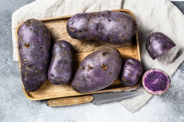 Kesme tahtasında çiğ patates. Gri arka plan. Üst görünüm